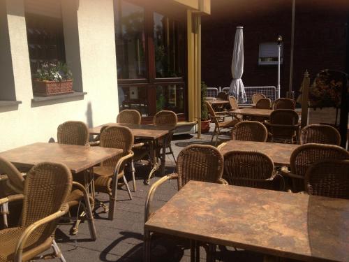 an empty patio with tables and chairs and umbrellas at Hotel Flora in Dormagen