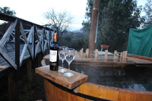 una botella de vino y copas en una mesa de madera en Cabana Quillon, en Quillón