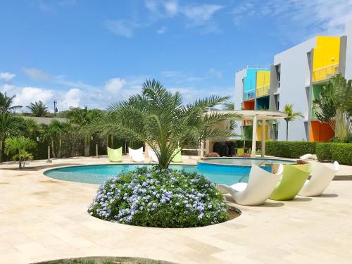 a resort pool with chairs and a palm tree at Isla Bonita Tropical 107 in Palm-Eagle Beach
