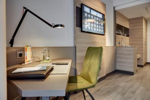 an office with a desk and a green chair at Lindner Hotel Dusseldorf Airport, part of JdV by Hyatt in Düsseldorf
