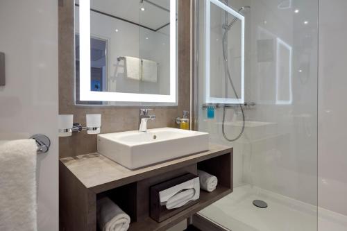 a bathroom with a white sink and a shower at Lindner Hotel Dusseldorf Airport, part of JdV by Hyatt in Düsseldorf