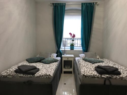 ポズナンにあるMarii Konopnickiej 20の緑のカーテンと窓が備わる客室で、ベッド2台が備わります。