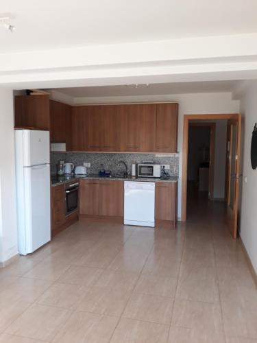 cocina grande con electrodomésticos blancos y armarios de madera en Apartment Verge de Montserrat, en Cambrils