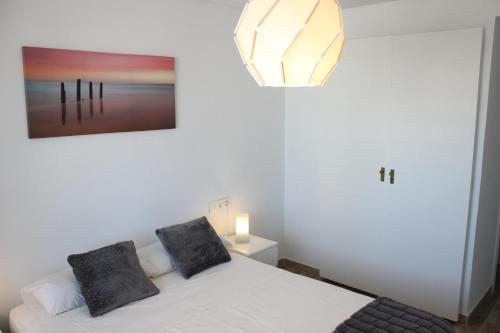 トレモリノスにあるNogalera Beach Apartmentのベッドルーム1室(白いベッド1台、黒い枕2つ付)
