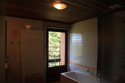Green Hill Guest House and Apartment في أوفريس: حمام مع حوض استحمام ونافذة