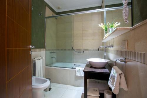un bagno con lavandino, WC e vasca di Hotel Roble Blanco a Chascomús