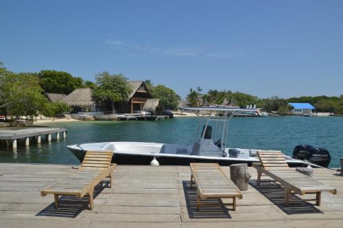 a boat is docked at a dock with chairs at Isla Los Erizos EcoHouse in Isla Grande