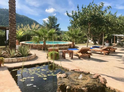 a pool with benches and a pond with water lilies at Villa Sa Paissa in Cala Vadella