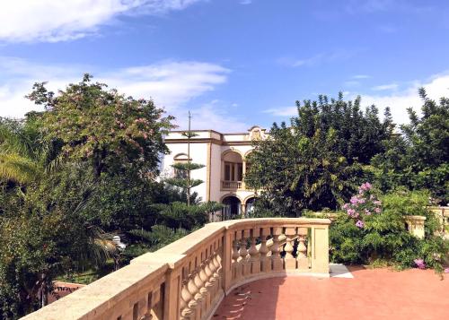a bridge in a garden with a house in the background at VILLA MARRONE - Relais - in Marsala