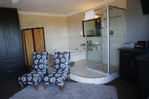 a bathroom with a shower and two chairs and a tub at Bluewater Beachfront Guest House in Port Elizabeth