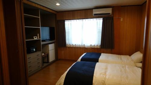 a bedroom with a bed and a window and a television at Minpaku Nagashima room2 / Vacation STAY 1036 in Kuwana