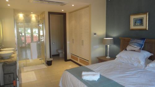 a bedroom with a bed and a bathroom with a shower at Island View Apartment by Simply-Seychelles in Eden Island