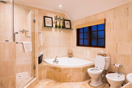 a bathroom with a tub and a toilet and a sink at Five Burnham Guest House in Durban