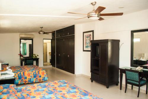 a bedroom with two beds and a desk and a ceiling fan at Hotel Del Sol in Cancún