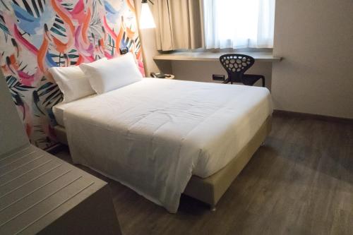 a bedroom with a white bed with a chair and a window at Hotel San Giovanni Roma in Rome