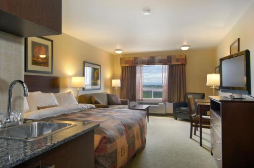 ein Hotelzimmer mit einem Bett und einem Waschbecken in der Unterkunft Ramada by Wyndham High River in High River