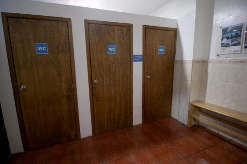 three wooden doors in a room with a bench at Hostel Hospedarte Centro in Guadalajara