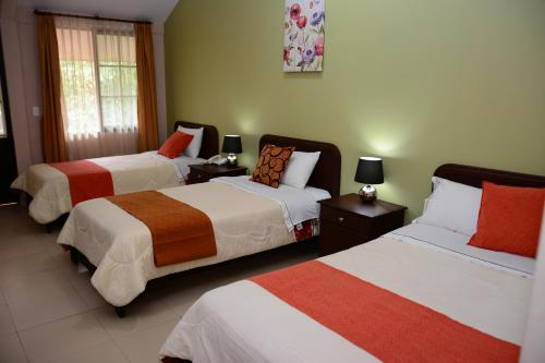 a bedroom with two beds and two lamps on tables at Hostal La Molienda in Puyo
