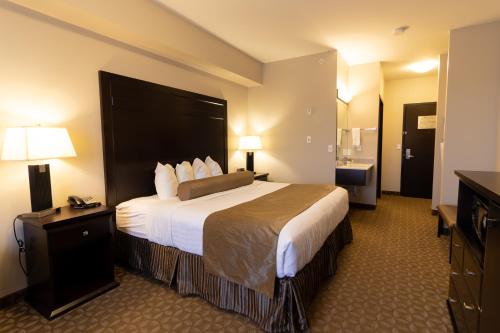 a hotel room with a large bed and a bathroom at Kanata Whitecourt in Whitecourt