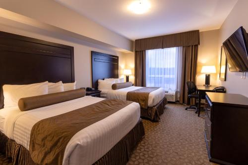 a hotel room with two beds and a flat screen tv at Kanata Whitecourt in Whitecourt