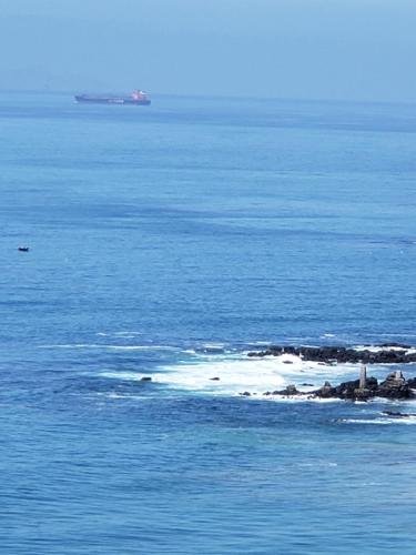 an island in the ocean with a ship in the distance at Calfia Condo in Rosarito