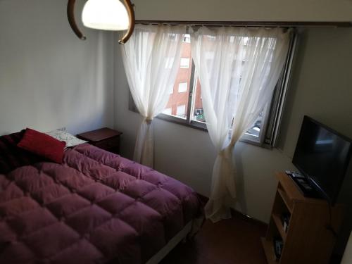 a bedroom with a purple bed and a window at Departamento Víctoria in Mar del Plata