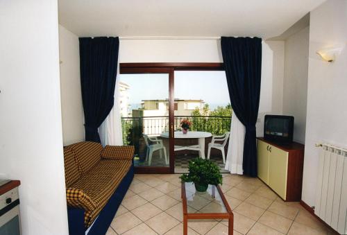 een kamer met een balkon met een tafel en een televisie bij Ilios Residence in Lido di Jesolo