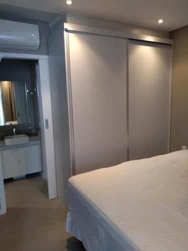 a bedroom with a white bed and a bathroom at Unique Santos - Flat 1105 in Santos