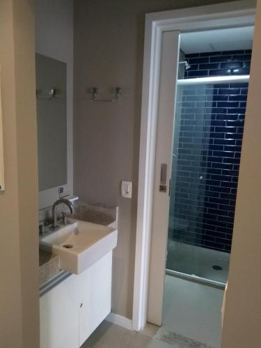 a bathroom with a sink and a glass shower door at Unique Santos - Flat 1105 in Santos