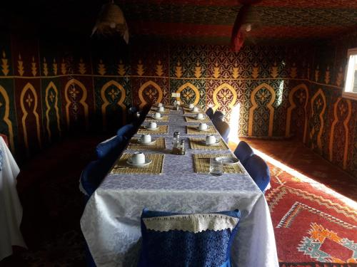 a long table in a room with blue chairs at Bivouac Le Ciel Bleu in Erfoud