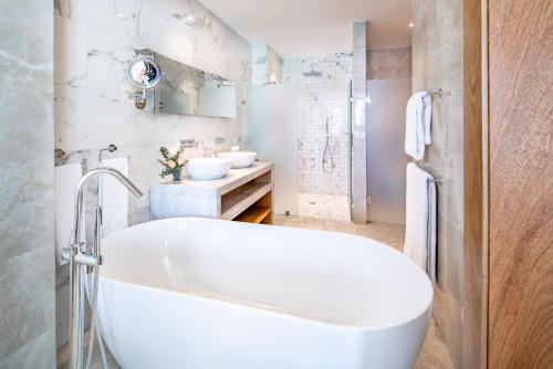 a white bathroom with a tub and a sink at Sanctuary Cap Cana, a Luxury Collection Resort, Dominican Republic, Adult All-Inclusive in Punta Cana