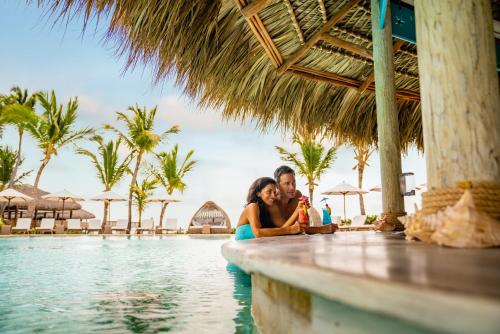 a couple sitting at the edge of a pool at a resort at Sanctuary Cap Cana, a Luxury Collection Resort, Dominican Republic, Adult All-Inclusive in Punta Cana
