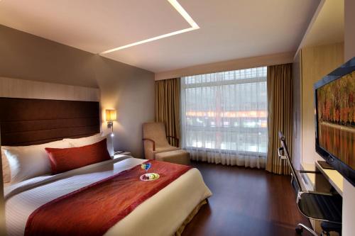 a hotel room with a bed and a large window at Mahagun Sarovar Portico Suites in Ghaziabad
