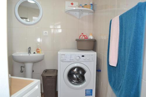 een kleine badkamer met een wasmachine en een wastafel bij Casinha de Muda da Feteira in Angra do Heroísmo