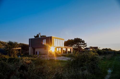 a house in a field with the sun shining on it at Studio Mb in Ouddorp