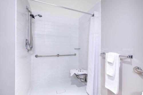 a white bathroom with a shower and a toilet at Microtel Inn & Suites by Wyndham Fort McMurray in Fort McMurray