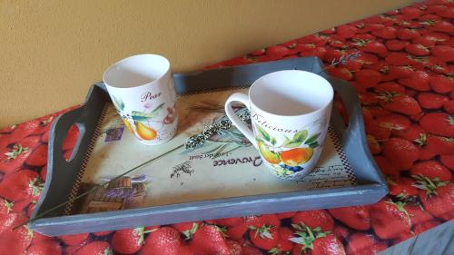 two coffee mugs sitting on a tray with strawberries at Casa Cesira in Tarzo