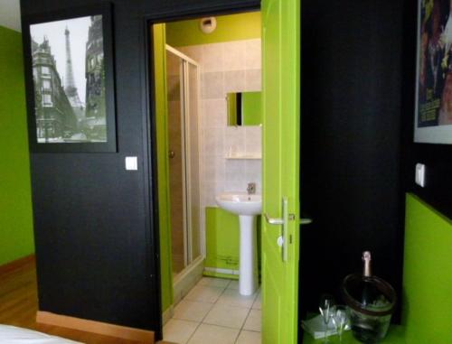 La salle de bains est pourvue d'une porte verte et d'un lavabo. dans l'établissement Hôtel Victor, à Beauvais