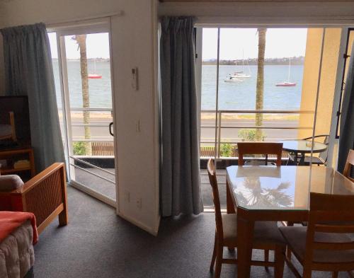 a living room with a table and a view of the ocean at Bucklands Beach Waterfront Motel in Auckland