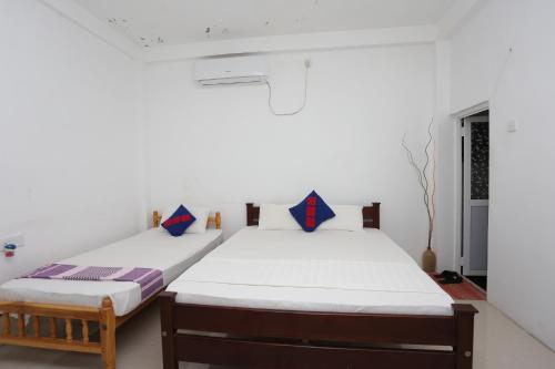 two beds in a room with white walls at Araliya White House in Negombo