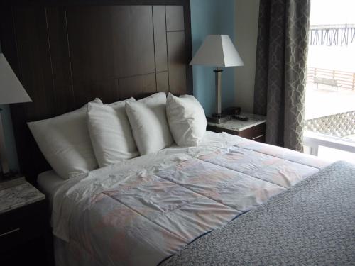 a bedroom with a bed with white pillows and a window at Dolphin Cove Motel in Pismo Beach