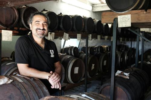 a man standing next to a bunch of wine barrels at B&B VILLA PAOLIDA,ACETO BALSAMICO & Tastings in Nonantola