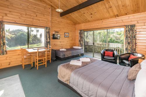 a bedroom with a bed and a desk and a table at Paparoa Park Motel in Punakaiki