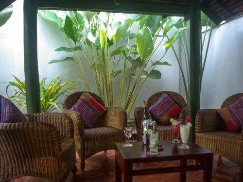 a room with chairs and tables and a large plant at Maison Houng Chanh - Luang prabang in Luang Prabang