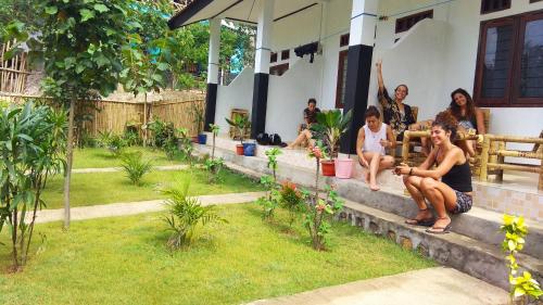 a group of people sitting on the porch of a house at Nanda Homestay in Kuta Lombok