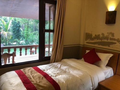 a bedroom with a bed and a large window at Jungle Safari Resort in Sauraha
