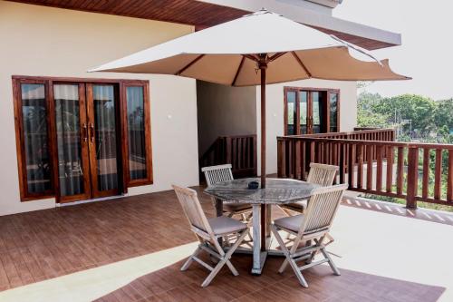 a table and chairs with an umbrella on a deck at Medewi Beach Inn in Pulukan