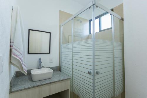a bathroom with a sink and a glass shower at Villa Ana Lucía. in Playa del Carmen