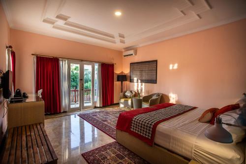 a bedroom with a large bed and red curtains at Laki Uma Villa - Male Only in Canggu