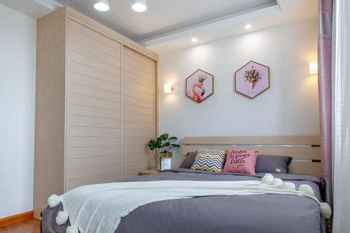 - une chambre avec un lit et deux photos sur le mur dans l'établissement Henan Kaifeng·Henan University· Locals Apartment 00170030, à Kaifeng